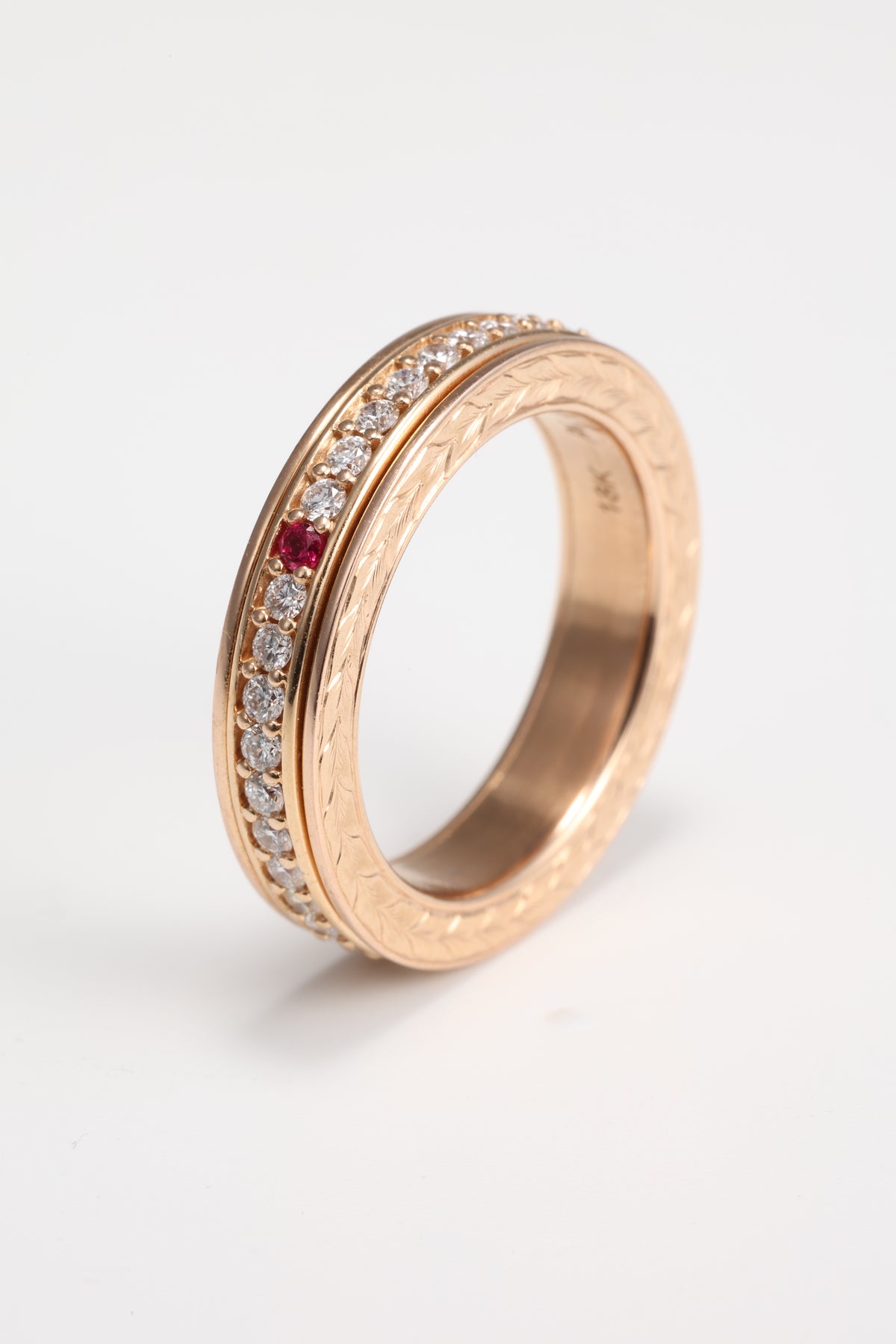 Ruby and diamond spinner ring showing hand-engraved rose gold side