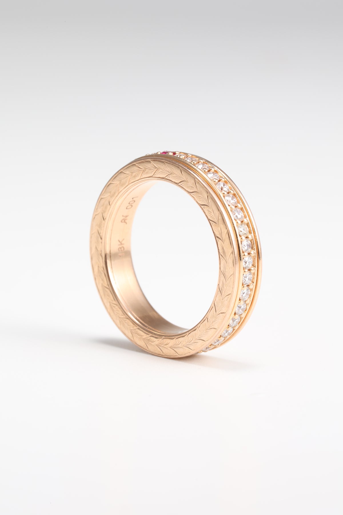 Rose gold spinner ring showing hand engraving and diamond-set band