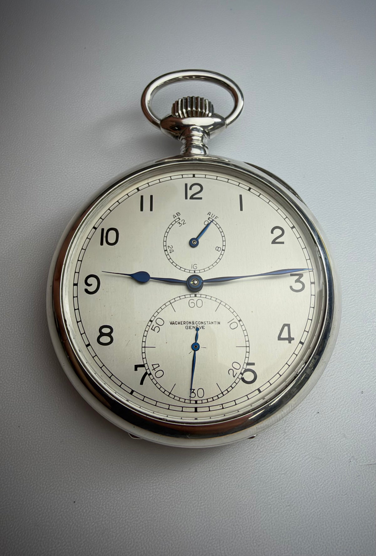 Silver-colored pocket watch with blue hands and two subdials